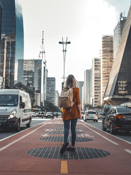 Photo by Guilherme Stecanella photography of woman walking in between road with vehicles